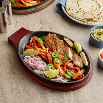 Choice 9 1/4" x 7" Oval Pre-Seasoned Cast Iron Fajita Skillet with Mahogany Finish Wood Underliner