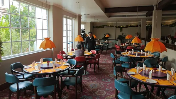 Restaurant dining room with round tables and teal chairs