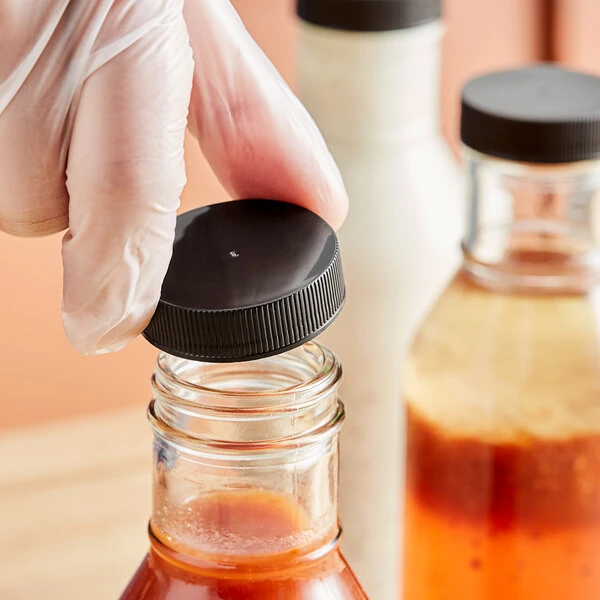 38/400 Black Ribbed Continuous Thread Lid with Pressure Sensitive Liner - 2,900/Case