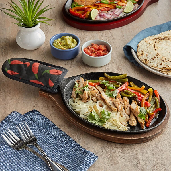 Choice 9 1/4" x 7" Oval Pre-Seasoned Cast Iron Fajita Skillet with Oak Finish Wood Underliner and Chili Pepper Cotton Handle Cover