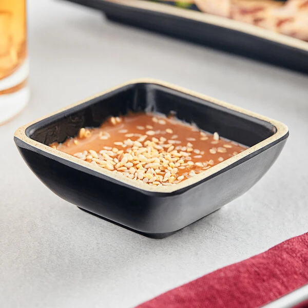 Acopa Ugoki 2 oz. Matte Black Square Melamine Sauce Dish with Ivory Rim - 12/Pack