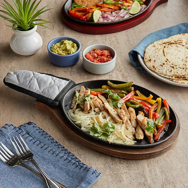Choice 9 1/4" x 7" Oval Pre-Seasoned Cast Iron Fajita Skillet with Oak Finish Wood Underliner and Gray Silicone Handle Cover