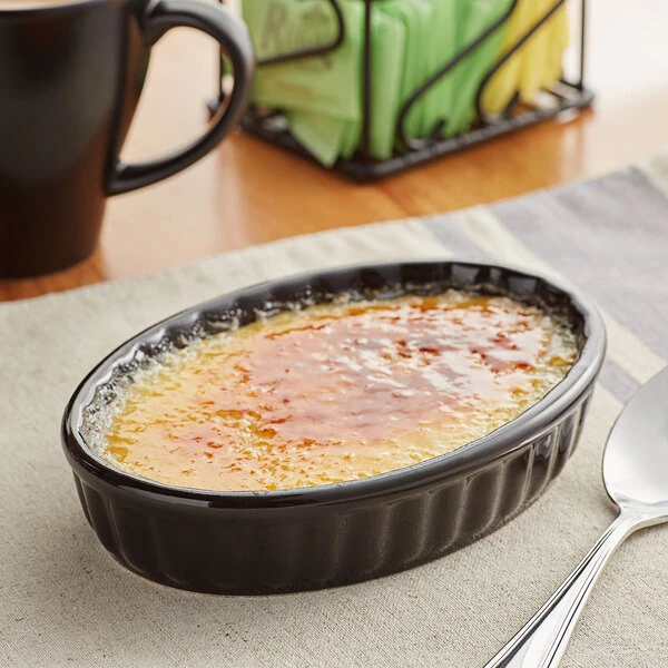 Acopa 6 oz. Oval Glossy Black Fluted Stoneware Souffle / Creme Brulee Dish - 36/Case