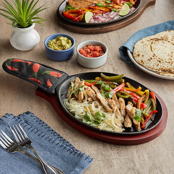 Choice 9 1/4" x 7" Oval Pre-Seasoned Cast Iron Fajita Skillet with Mahogany Finish Wood Underliner and Chili Pepper Cotton Handle Cover